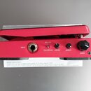 Červený kytarový efekt s nápisy INPUT, WAH/VOL, WAH/BYPASS, MIN VOL, QUALITY a RANGE. Na přístroji jsou umístěny jeden vstupní konektor, dva přepínač…