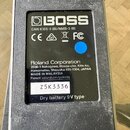 Záběr na spodní stranu černého efektového pedálu s nalepeným informativním štítkem. Na štítku je bílé logo BOSS a nápisy CAN ICES-3 (B)/NMB-3 (B), CE…