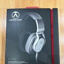 Fotografie zobrazuje černé obalové pouzdro s červeným vnitřkem. Na přední straně je obrázek stříbrných sluchátek s logem a nápisem AUSTRIAN AUDIO. Do…