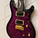Elektrická kytara s fialovým lakem a výraznou strukturou dřeva. Má dva humbuckery značky EMG, zlatý hardware včetně mostu a knoflíků. Na hrazence jso…