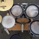 Sada bubnů v černé barvě s několika cymbály. Na cymbálech je viditelný nápis METEOR a logo MEINL. Na pedálech je nápis FAZZA THE LEGEND. Povrchy blan…