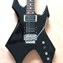 Černá elektrická kytara s ostrými hranami korpusu a hnedým hmatníkem. Nástroj má dva humbuckery, třicet strunových ladíček a pákový systém s nápisem…