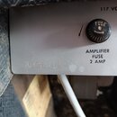Detail šedého kovového panelu přístroje s černým krytem pojistky. Na panelu je nápis 117 VO, AMPLIFIER FUSE 2 AMP a vyražené sériové číslo A036342. N…
