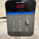 Šedý elektronický modul s černým displejem, na kterém svítí červená čísla 005. V horní části je bílý nápis Millenium a nad ním modrý štítek s nápisem…