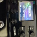 Detailní záběr na černý efektový pedál s displejem. Na obrazovce je bílým textem napsáno LINE 6, HX STOMP a Firmware 3.80.0. Pod displejem jsou umíst…