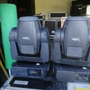 Dvě černé světelné hlavice typu moving head umístěné vedle sebe na transportním case. Na přední části obou jednotek je nápis MAC 250 a na spodní zákl…