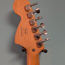 Zadní strana dřevěné hlavy kytary s šesti chromovanými ladičkami. Na dřevě je černý nápis: Designed and Backed by Fender Crafted in Indonesia s/n ICS…