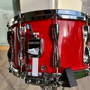Červený snare drum s chromovaným obručováním a ladicími šrouby. Na mechanismu napnutí je viditelné logo YAMAHA. Povrch nástroje je lesklý, v dobrém s…