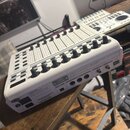 Bílý MIDI kontrolér s posuvníky a otočnými knoflíky. Na horní části je nápis B-CONTROL FADER BO2000 a USB+MIXFADER+CONTROLLER. Na zadní straně je vid…
