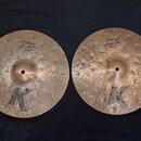 Dvě mosazné činely s výrazným kladivováním a černým logem K ve spodní části. Levý činele má nápisy Custom Special Dry a HIHAT BOTTOM 14" 70 cm. Pravý…