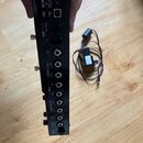 Zadní strana černého elektronického zařízení s řadou konektorů. Jsou zde nápisy DC IN 9VDC 3A, USB, MIDI OUT/THRU a IN, OUTPUT BAL L/R (LEFT, RIGHT),…