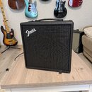 Černý kytarový kombo zesilovač s logem Fender v horní levé části mřížky. Zesilovač má hranatý tvar, černé povrchové provedení a nahoře integrovanou r…