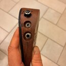 Detailní pohled na hranu hnědého dřevěného nástroje. Jsou zde vidět dva konektory s nápisy DC 9V (u horního) a OUT (u spodního), oraz jeden kovový př…