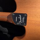 Detail zadní strany kytary s viditelným spojem krku a těla. Na černé kovové spojovací desce je bílý nápis Fender a text CORONA, CALIFORNIA. Vedle log…