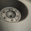 Fotografie zachycuje detail vnitřku černého reproduktoru, konkrétně jeho magnetickou součástku. Centrální část je upevněna pěti křížovými šrouby. Pov…