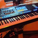 Černý digitální klavír s bílými a černými klávesami. Na panelu je viditelný nápis YAMAHA, displej a množství modře podsvícených tlačítek a posuvníků.…