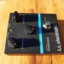 Černý kytarový efekt s nápisy t.c. electronic, VINTAGE OVERDRIVE a GUITAR EFFECTS TECHNOLOGY. Na horní straně jsou tři černé otočné ovnovky s popisky…