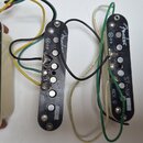 Tři kytarové snímače typu single-coil s černými plastovými kryty. Každý má bílou nálepku s nápisy: první zleva „ST-BR REV. D“, prostřední „ST-MD REV.…