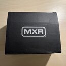 Černá čtvercová krabice z kartonu s bílým logem MXR uprostřed. Povrch krabice vykazuje známky opotřebení v podobě několika viditelných záhybů a pomač…