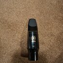 Černý mouthpiece z plastu nebo ebonitu. Na povrchu je zlatým písmem logo Yamaha a označení modelu 6C. Nástroj vykazuje mírné známky používání v podob…