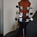 Záběr na hlavu kytary z tmavého dřeva s chromovanými ladičkami. Na každém z šesti ladiček je viditelné logo s písmenem „E“ a nápisem „Epiphone“. Povr…