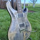 Elektrická kytara s tělem z plaménkového dřeva v přírodní šedohnědé barvě. Nástroj má dva humbuckery, tremolo s páčkou a dvě ovládací knoflíky. Na hm…