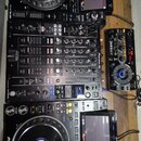 Sada DJského vybavení značky Pioneer DJ v černé barvě. Sestává ze dvou přehrávačů s nápisem Pioneer DJ a CDJ-3000, centrálního mixeru s nápisem Pione…