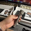 Ruka drží šedý dynamický mikrofon s kovovou síťkou. Na prstenci pod hlavou mikrofonu je nápis WA-19. V pozadí jsou dvě bílé krabice s černou pěnovou…