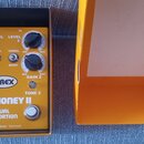 Kytarový efekt v oranžovém šasi s nápisy T-REX, MUDHONEY II a DUAL DISTORTION. Na spodní části je text By T-REX Effects Denmark. Zařízení má čtyři če…