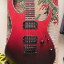 Elektrická kytara s červeným gradientním lakem, který přechází do černé v dolní části těla. Nástroj má dva humbuckery, jeden ovládací knoflík hlasito…