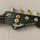 Černá hlava basové kytary s pěti zlatými ladičkami. Na povrchu je bílý nápis Fender® a zlatý nápis JAZZ BASS® SPECIAL. Povrch je hladký a bez viditel…