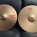 Dvě mosazné činely typu hi-hat s vlnovitým okrajem. Na levém je červený nápis SOUND EDGE HI-HAT BOTTOM 14" a na pravém TOP SOUND EDGE HI-HAT 14". Oba…