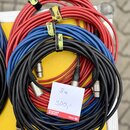 Svršek červeného, modrého a černého audio kabelu s XLR konektory. Kabely jsou svázány žlutými stahovacími pásky, na kterých je nápis 8m. Na černém ka…