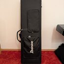 Černý obal na hudební nástroj s dvěma zipovými kapsami. Na spodní kapse je bílý nápis Ibanez. Obal má připevněnou rukojet pro přenos.