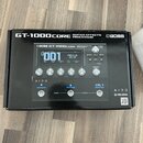 Krabice s nápisy GT-1000 CORE GUITAR EFFECTS PROCESSOR a logem BOSS. Na povrchu krabice je obrázek procesoru s displejem, na kterém je text 001 a PRE…