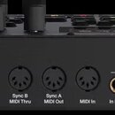 Zadní strana černého elektronického přístroje s bílým nápisem Elektron a Syntakt. Jsou zde vidět konektory Power, 12VDC 2A, USB, Sync B MIDI Thru, Sy…