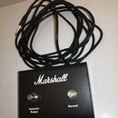 Černý kytarový efekt s nápisem Marshall. Na horní straně jsou dvě stoupavá tlačítka s popisky Dynamic Range a Reverb. K zařízení je připojen dlouhý č…