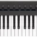 Černý klavírní kontrolér s bílými a černými klávesami. Na pravé straně je nápis KORG a model Keystage POLY IC MIDI KEYBOARD, dále je zde označení Pol…