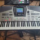 Stříbrný digitální klavír s černými ovládacími panely a klasickou klaviaturou. Na levé straně je nápis Roland a na pravé straně označení e-80 MUSIC W…