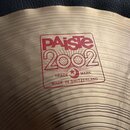 Detail činely z mosazi s koncentrickými rýhami. Na povrchu je červený nápis PAiste 2002, pod kterým je v rámečku text TRADE MARK a MADE IN SWITZERLAN…