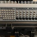 Zadní strana mixážního pultu v kovovém šedém provedení. Na horní hraně je uveden nápis BEHRINGER EURORACK MX 2642A. Zařízení obsahuje řadu vstupů a v…