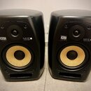 Dva černé studiové monitory s žlutými membránami basových reproduktorů. Na přední straně obou reproduktorů je bílý nápis KRK Global Sonic a označení…