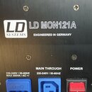 Detail zadní strany černého elektronického zařízení s kovovým povrchem. Je zde uveden nápis LD SYSTEMS, model LD MON121A a text ENGINEERED IN GERMANY…