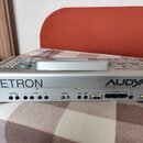 Stříbrný klavír/arranger s rukojetí na horní straně. Na zadní straně je nápis KETRON a AUDYLA 4 advanced music station. Jsou zde viditelné různé kone…