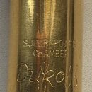Detail zlatavého kovového nástavce s nápisy. Jsou zde vyryty slova SUPER POWER CHAMBER, pod nimi značka Dukoff a níže text MIAMI, FLORIDA. Povrch vyk…
