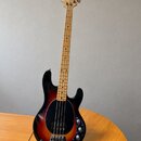Čtyřstrunná elektrická basová kytara s tělem v červeno-žlutém sunburst provedení a černým pickguardem. Na hlavě hředu je viditelné logo Rickenbacker.…