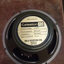 Kruhlový reproduktor s šedým rámem a žlutou štítkovou nálepkou. Na nálepce je uveden nápis Celestion, Model number G 12 M, Power capacity 25 watts, I…