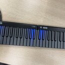 Černá elektronická klaviatura tvořená dvěma spojitými moduly. Na horní hraně obou částí je bílý nápis LUMI a ovládací tlačítka. Některé klávesy jsou…