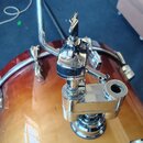 Detail chromovaného držáku na činely namontovaného na buben s žlutým přechodem do červené barvy. Na boku držáku je vyryt nápis „SONOR“. Povrch chromu…