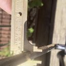 Detailní záběr na hřifo nástroje s kovovým mechanismem, který je měřen mosazným pravítkem. Na pravítku jsou viditelné stupnice s čísly 10, 20, 30, 40…